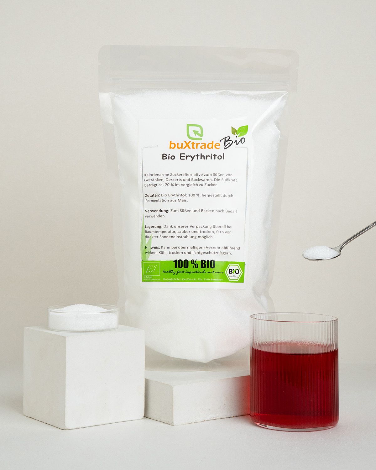 Ein Beutel buxtrade Bio Erythritol mit einem Glas Getränk und einem Löffel Erythritol.