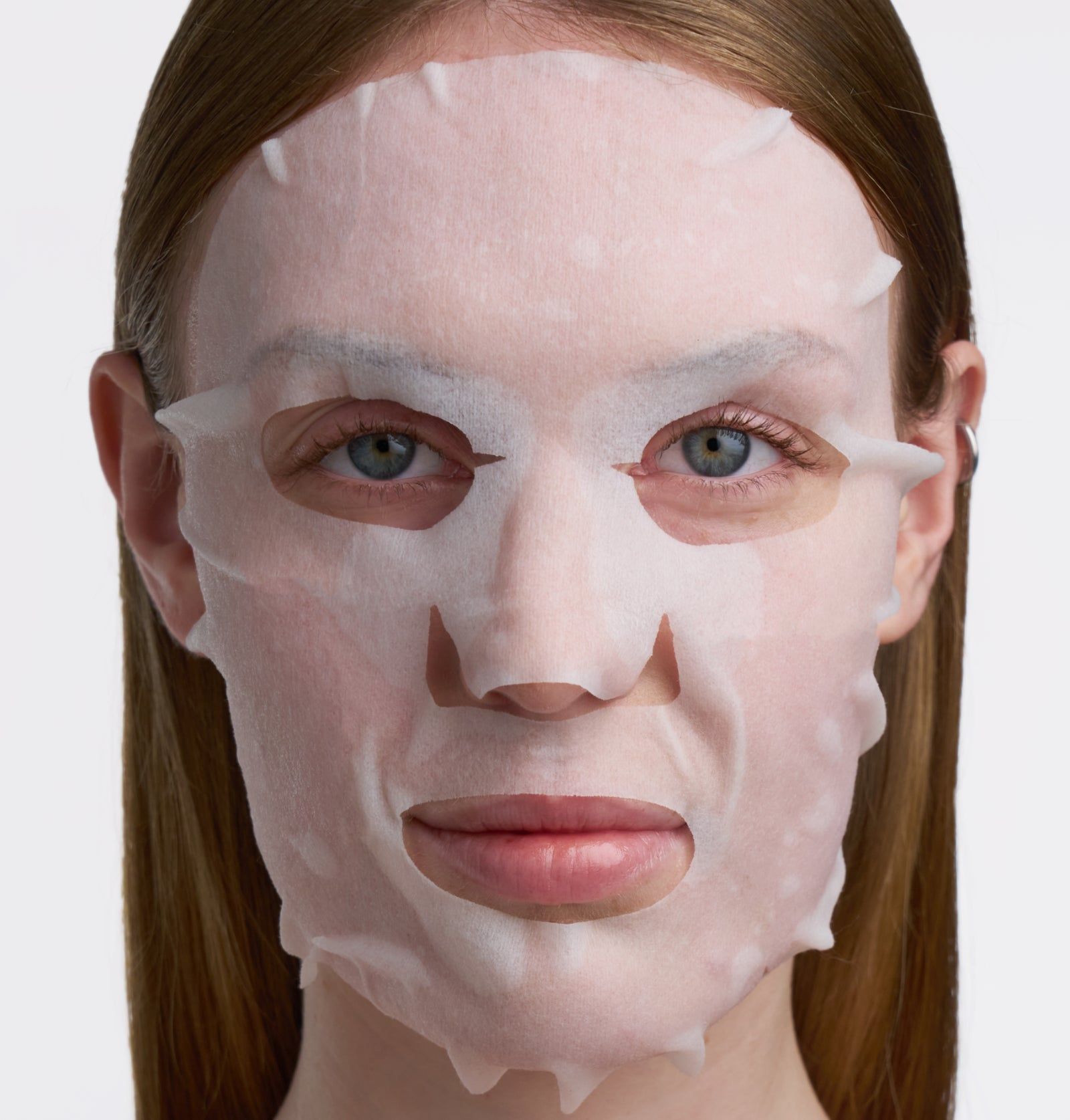 Gesichtsmaske auf dem Gesicht einer Frau. Die Maske bedeckt die Haut, mit Aussparungen für Augen, Nase und Mund.