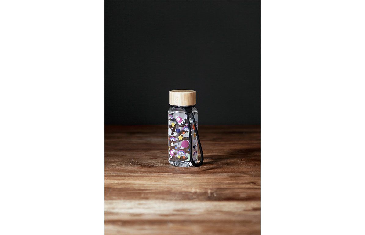 Trinkflasche mit Weltraum-Motiv, Bambusdeckel, schwarze Schlaufe. Auf Holzoberfläche, dunkler Hintergrund.