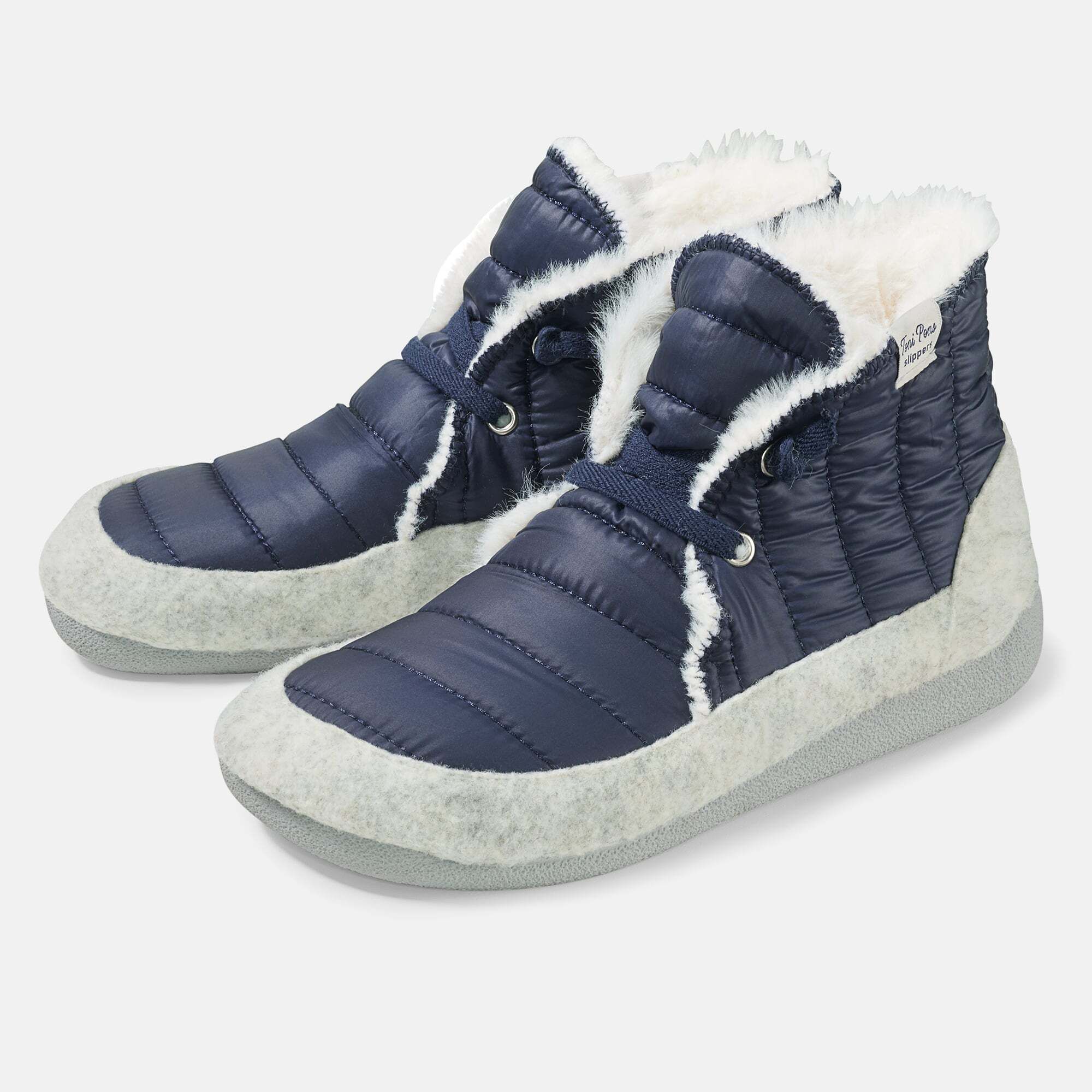 Blaue Pantoletten/Hausschuhe mit weißem Fellfutter. Schnürsenkel, breite Form. Außenmaterial gesteppt.