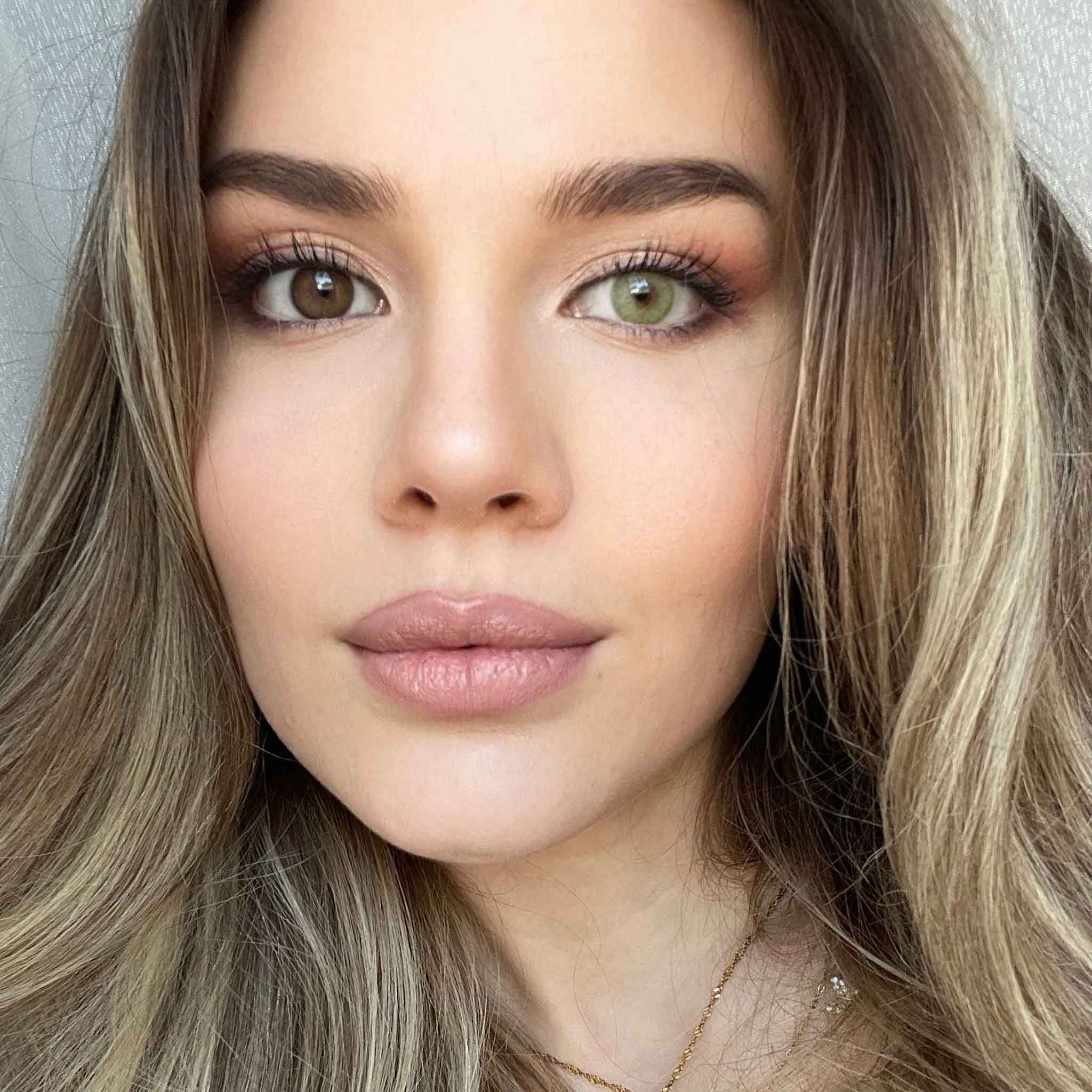 Porträt einer Frau mit unterschiedlichen Augenfarben. Ein Auge ist braun, das andere grün. Lange blonde Haare.