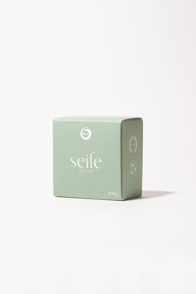 Hellgrüne Schachtel mit Aufschrift "seife Melisse". Auf der Seite Recycling-Symbole. Unten rechts "100g".