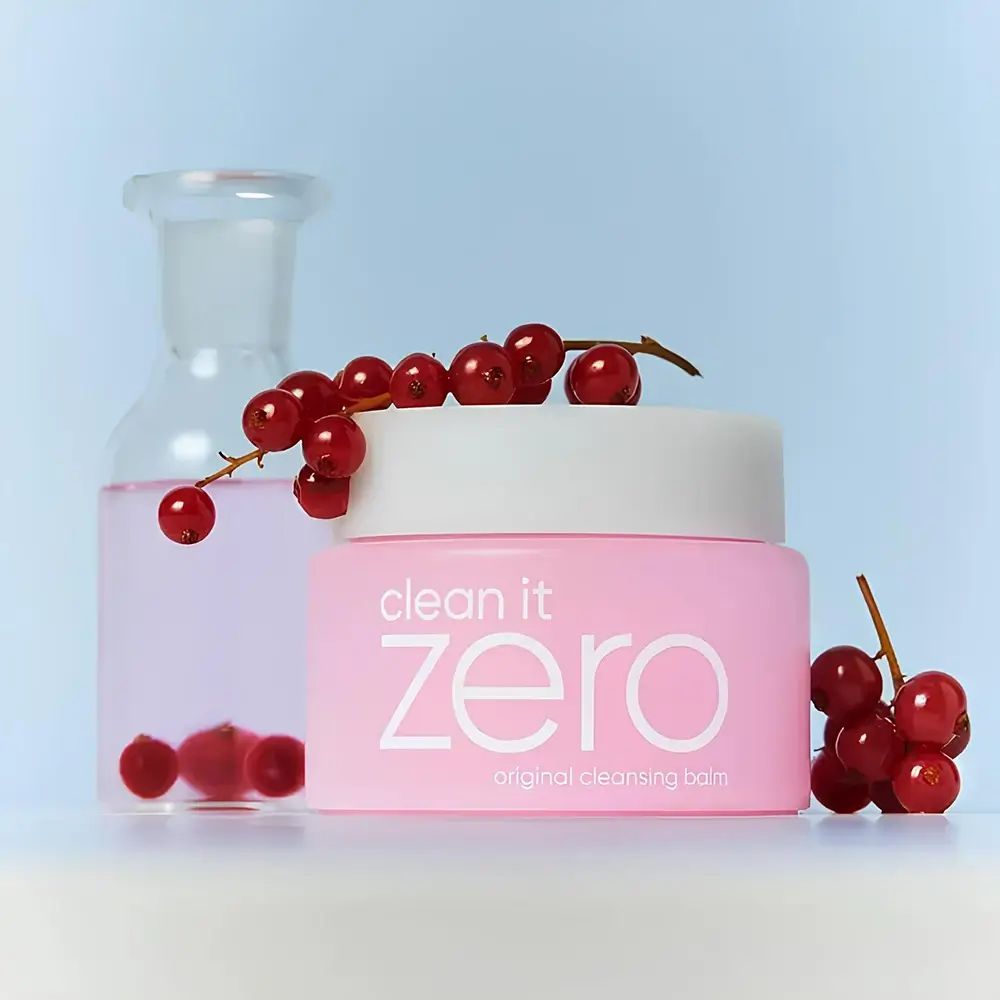 Rosa Dose mit weißem Deckel, daneben eine Glasflasche und rote Beeren. Aufschrift: clean it zero original cleansing balm.