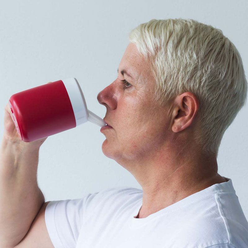 Person trinkt aus rotem Becher mit weißem Deckel und Trink-Trick-Aufsatz.