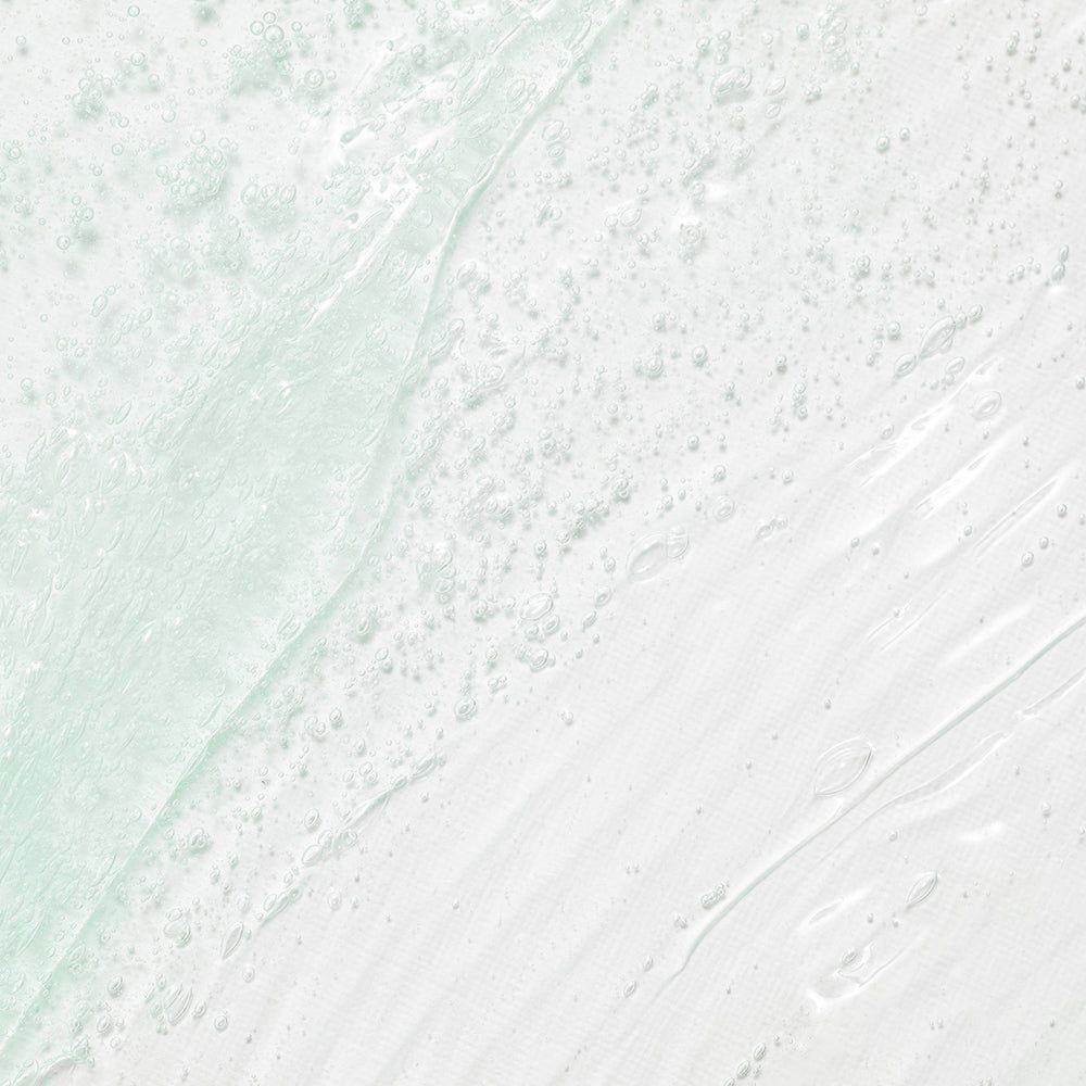 Eine hellgrüne, transparente Geltextur mit kleinen Luftbläschen, die auf einer weißen Oberfläche verteilt ist.