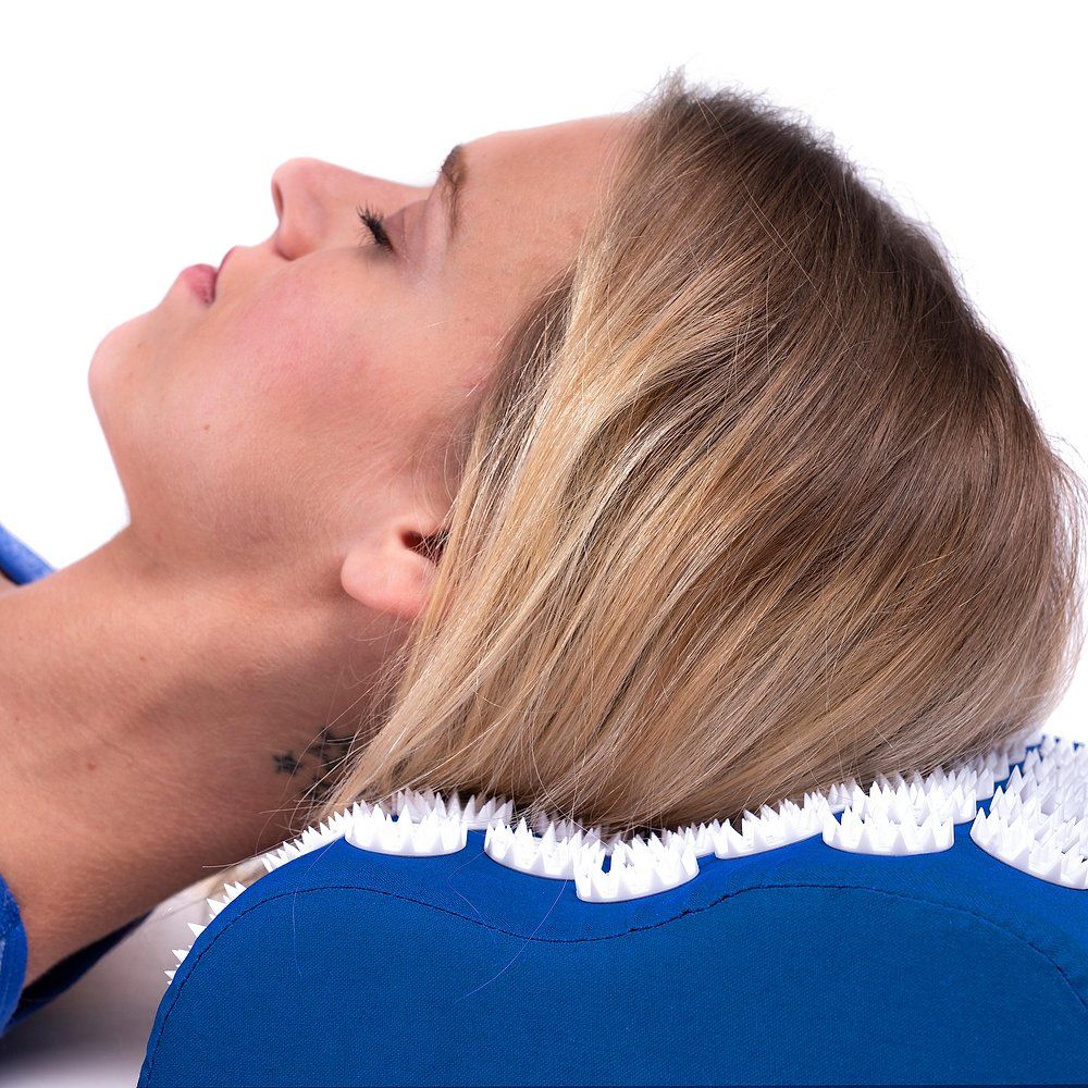 Nahaufnahme einer Frau, die auf einem blauen Akupressur-Kissen liegt.