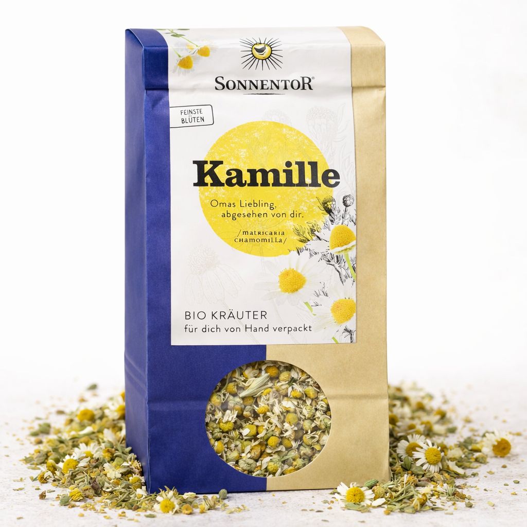 Packung SonnentoR Kamille lose Bio Kräuter, umgeben von verstreuten Kamillenblüten.