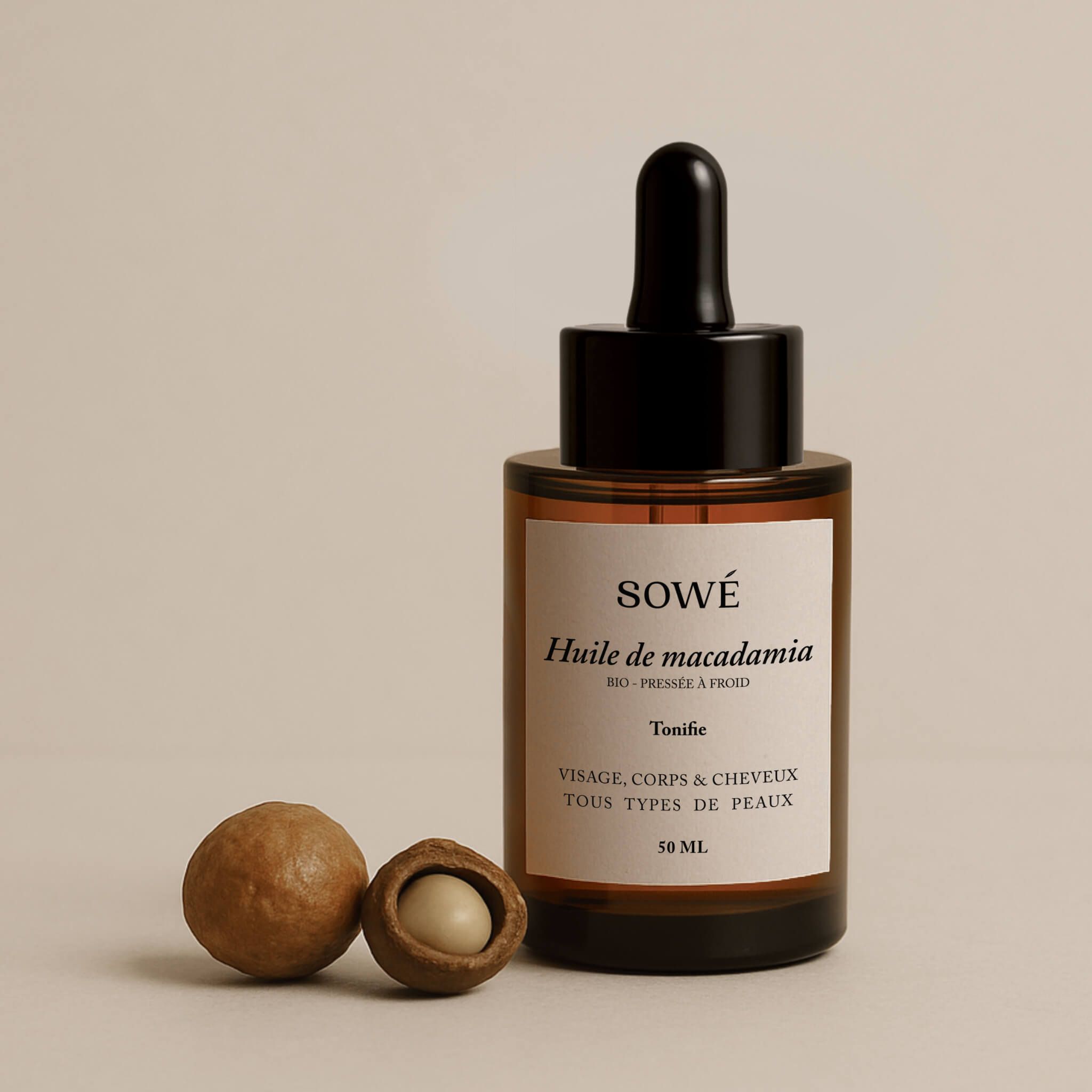 Braune Glasflasche mit Pipette und zwei Macadamia-Nüssen. Etikett mit "SOWÉ" und "Huile de macadamia".