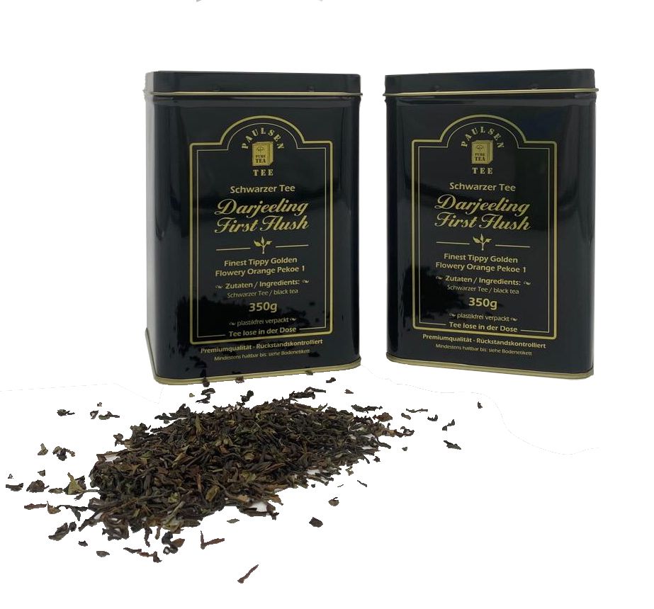 Zwei schwarze Teedosen mit goldfarbenem Etikett neben losem Tee. Aufschrift: Paulsen, Darjeeling First Flush, 350g.