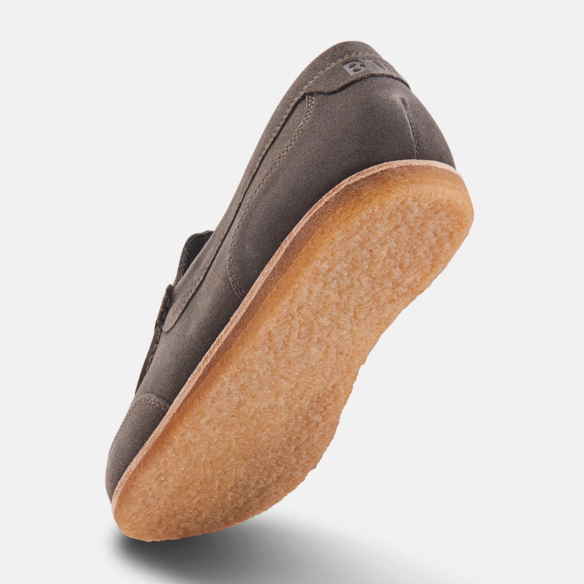 Grauer Wildleder-Slipper, Unteransicht. Hellbraune Sohle. Nahtdetails.