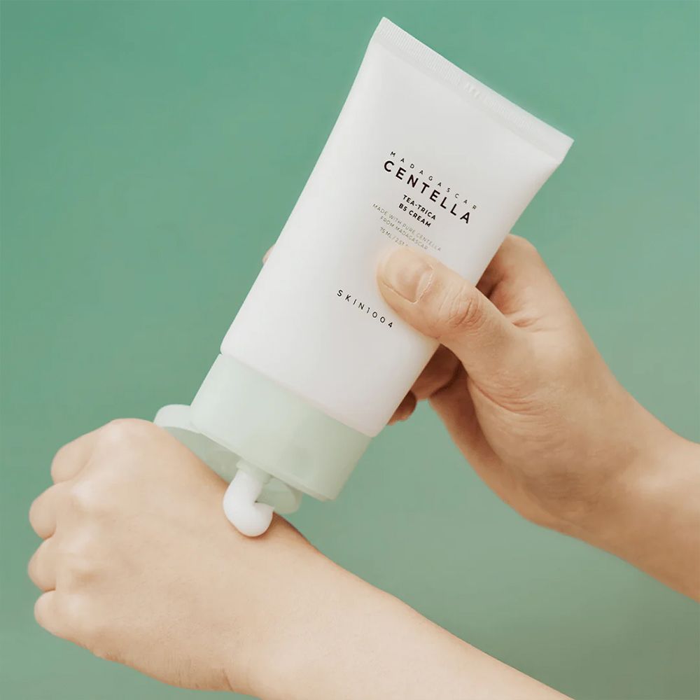 Hand trägt Creme aus der Tube SKIN1004 Centella Tea-Trica B5 Cream auf.