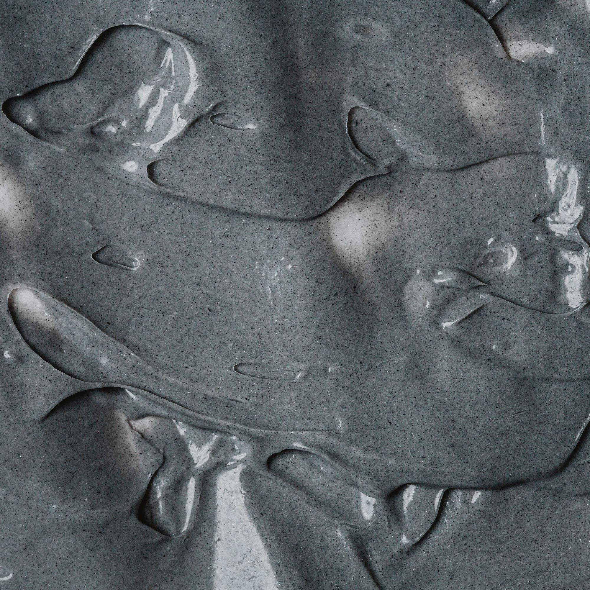 Nahaufnahme einer grauen Gesichtsmaske. Cremige Textur mit unregelmäßigen Formen.