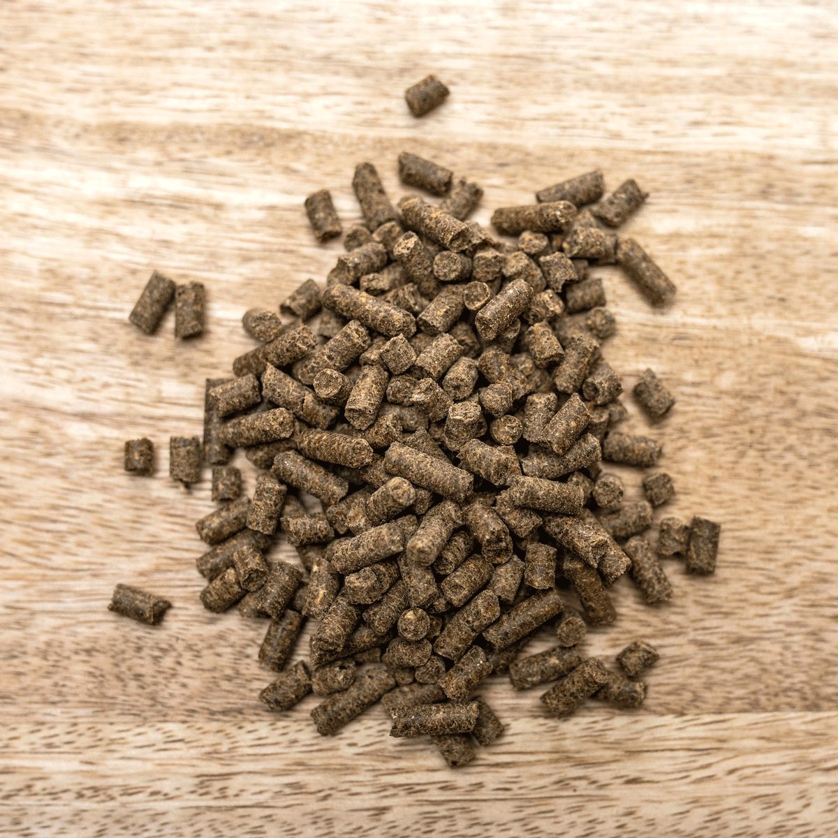 Haufen brauner Pellets auf Holzuntergrund. Tierfutter-Ergänzungsmittel.
