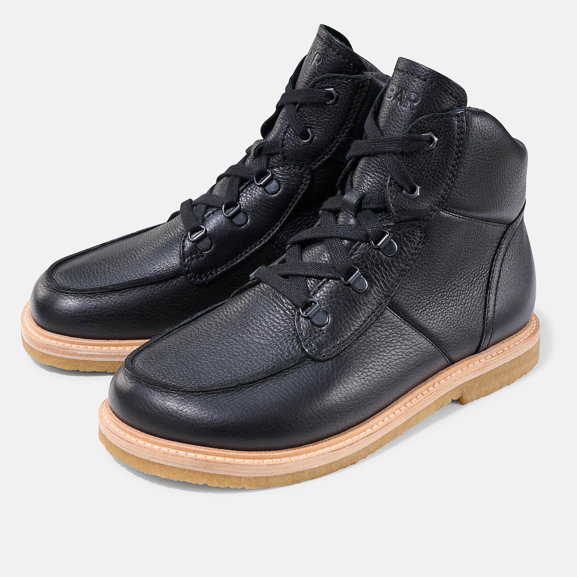 Schwarze Stiefeletten mit Schnürung und heller Sohle. Lederoptik. Zwei Schuhe nebeneinander.