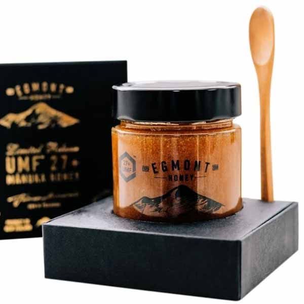 Glas mit Honig und Holz-Löffel auf schwarzem Podest, daneben eine schwarze Schachtel. Auf dem Glas steht "Egmont Honey".