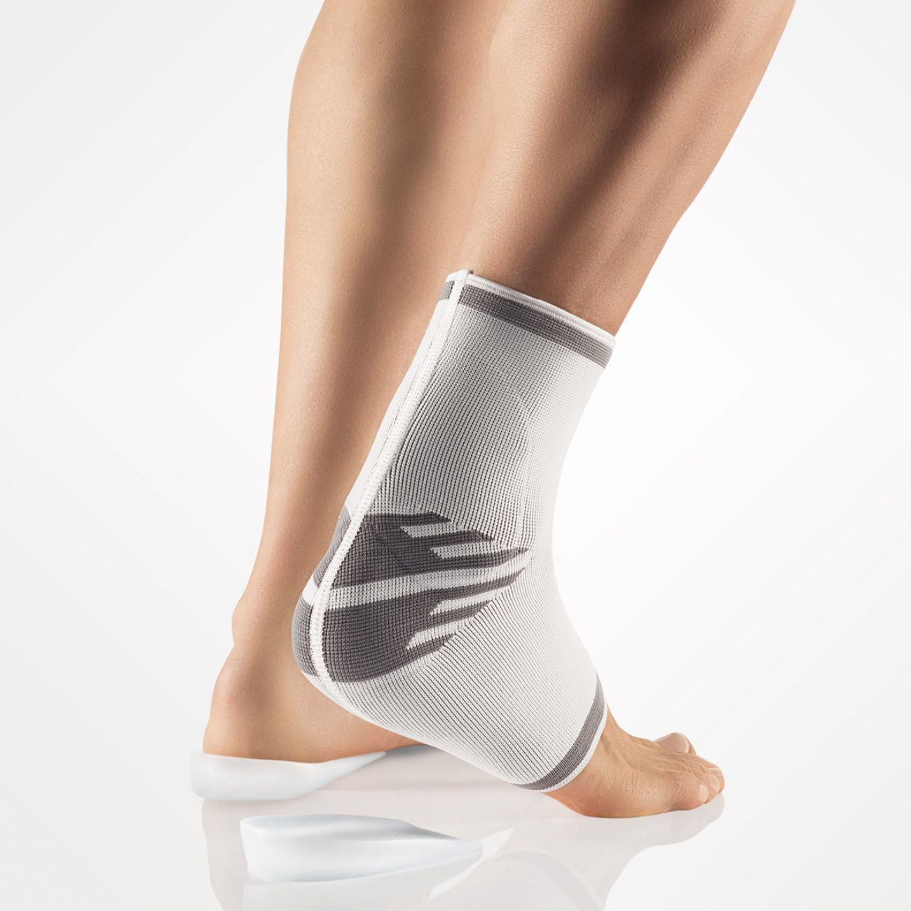 Achillessehnenbandage. Weiß-grau. Am Knöchel getragen. Gestricktes Material. Graue Akzente an den Rändern und am Fersenbereich.