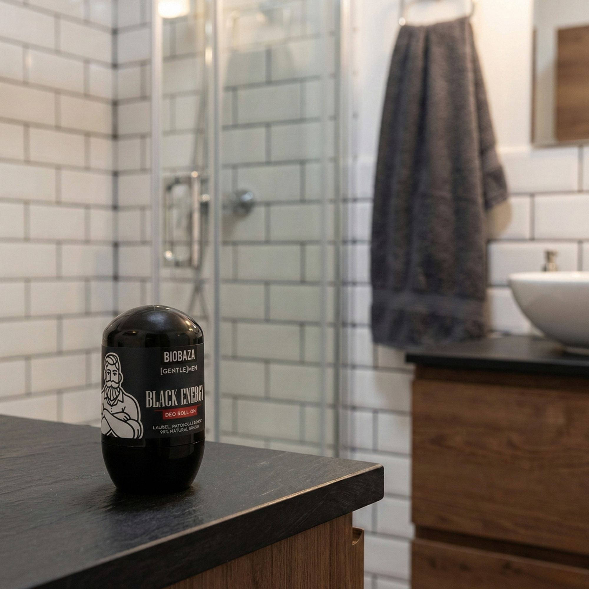 Schwarzer Deo Roll-On auf einer schwarzen Oberfläche. Badezimmer im Hintergrund. Aufschrift: BIOBAZA [GENTLE MEN] BLACK ENERGY.