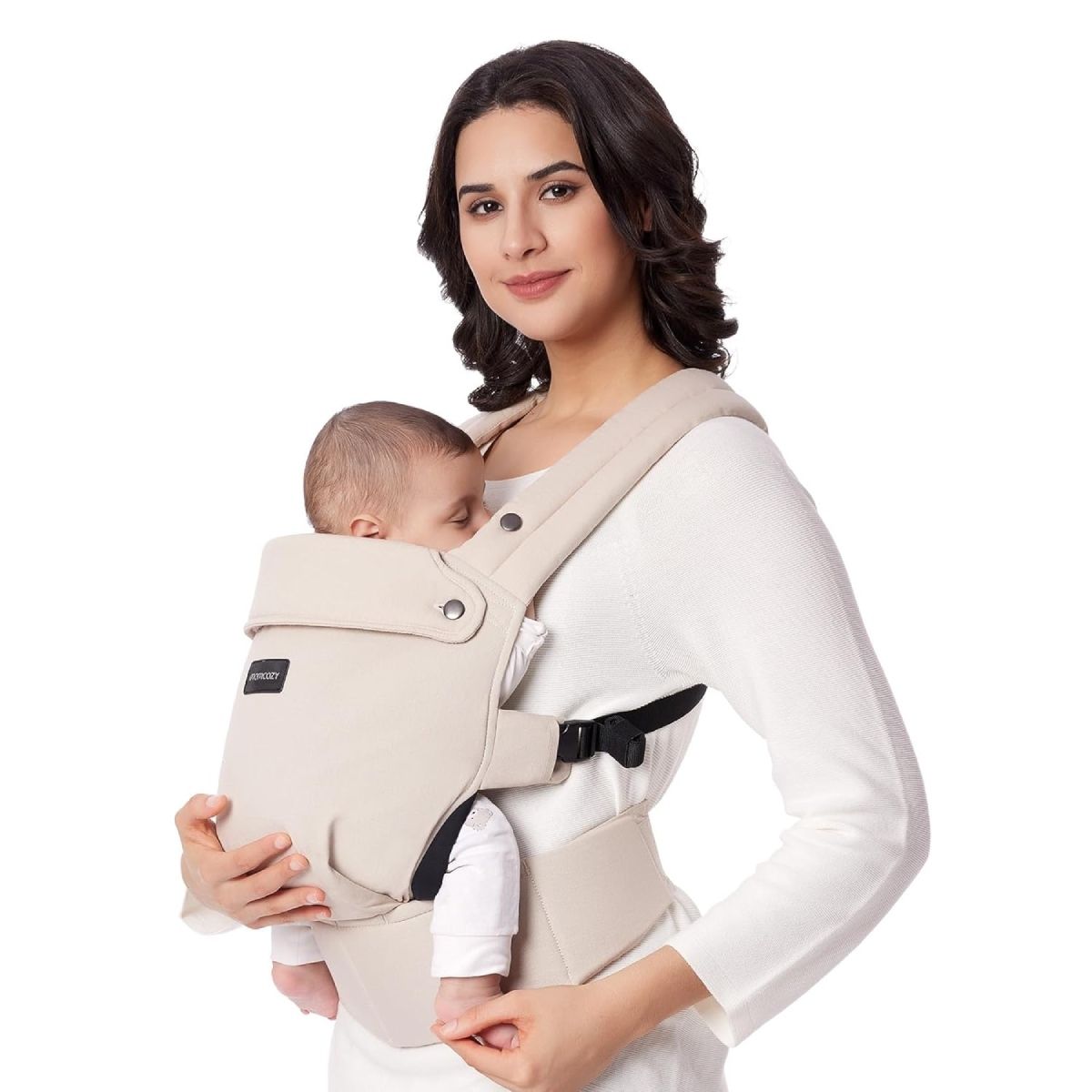 Frau hält Baby in beiger Babytrage. Momcozy-Logo sichtbar. Baby schläft.