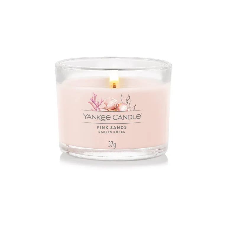 Kerzenglas mit rosa Wachs. Aufschrift: Yankee Candle, Pink Sands, Sables Roses, 37g. Mit brennender Flamme.