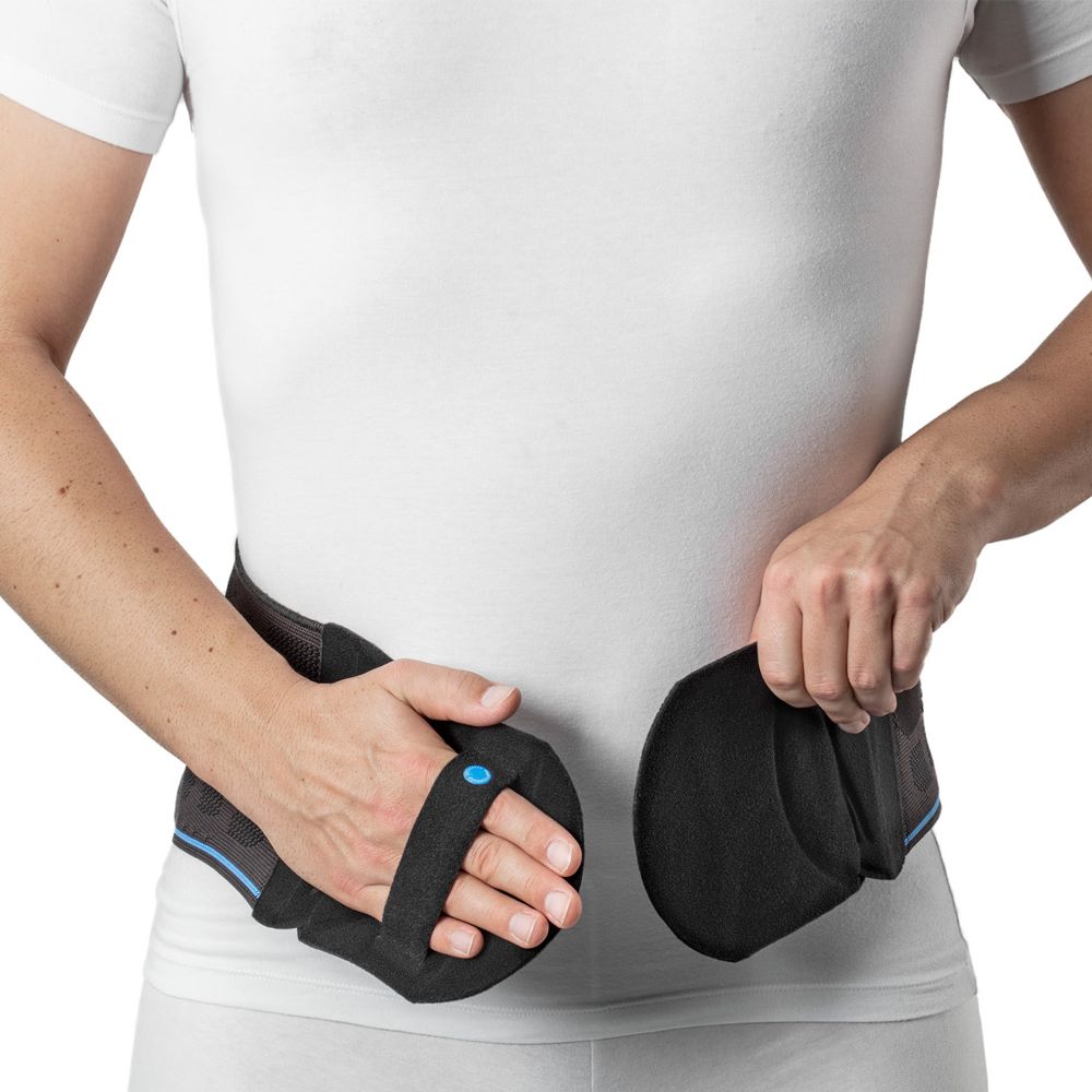 Person hält eine schwarze Lumbalbandage. Bandage hat Klettverschlüsse und blaue Akzente. Person trägt weißes T-Shirt.