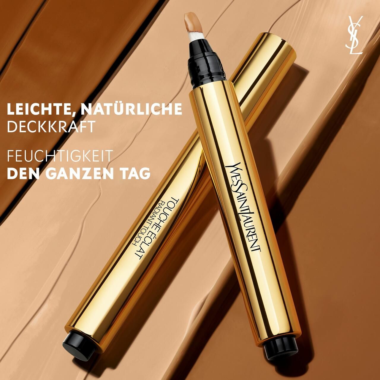 Zwei goldene Stifte mit schwarzer Spitze. Aufschrift: Yves Saint Laurent, Touche Éclat. Text: Leichte, natürliche Deckkraft.