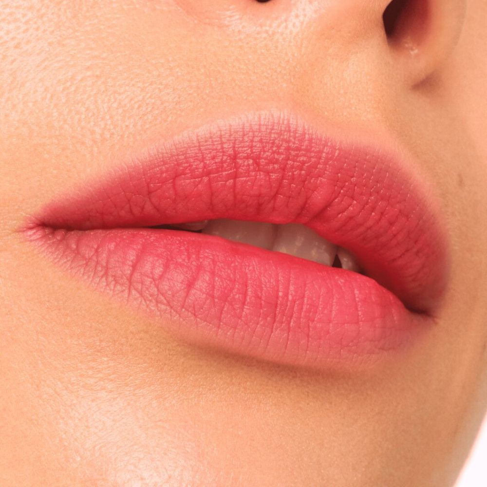 Nahaufnahme von Lippen, die mit rotem Lippenstift bemalt sind. Die Lippen sind leicht geöffnet.