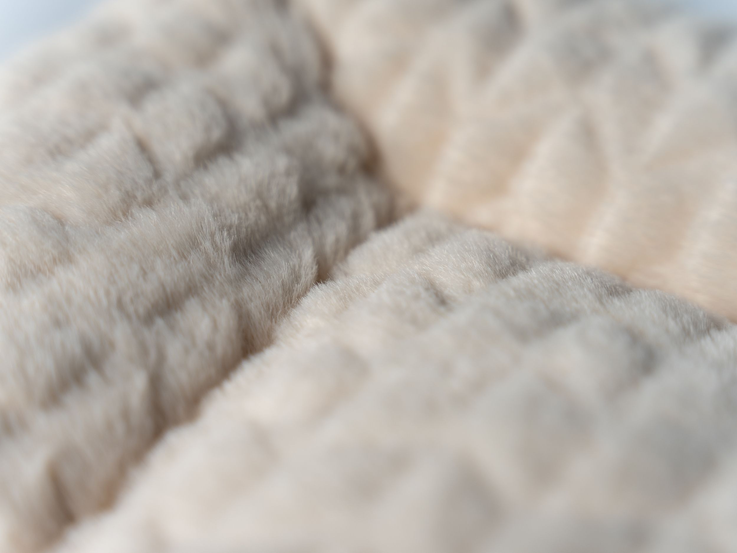 Nahaufnahme der cremefarbenen, gefütterten Liegedecke. Struktur erkennbar.