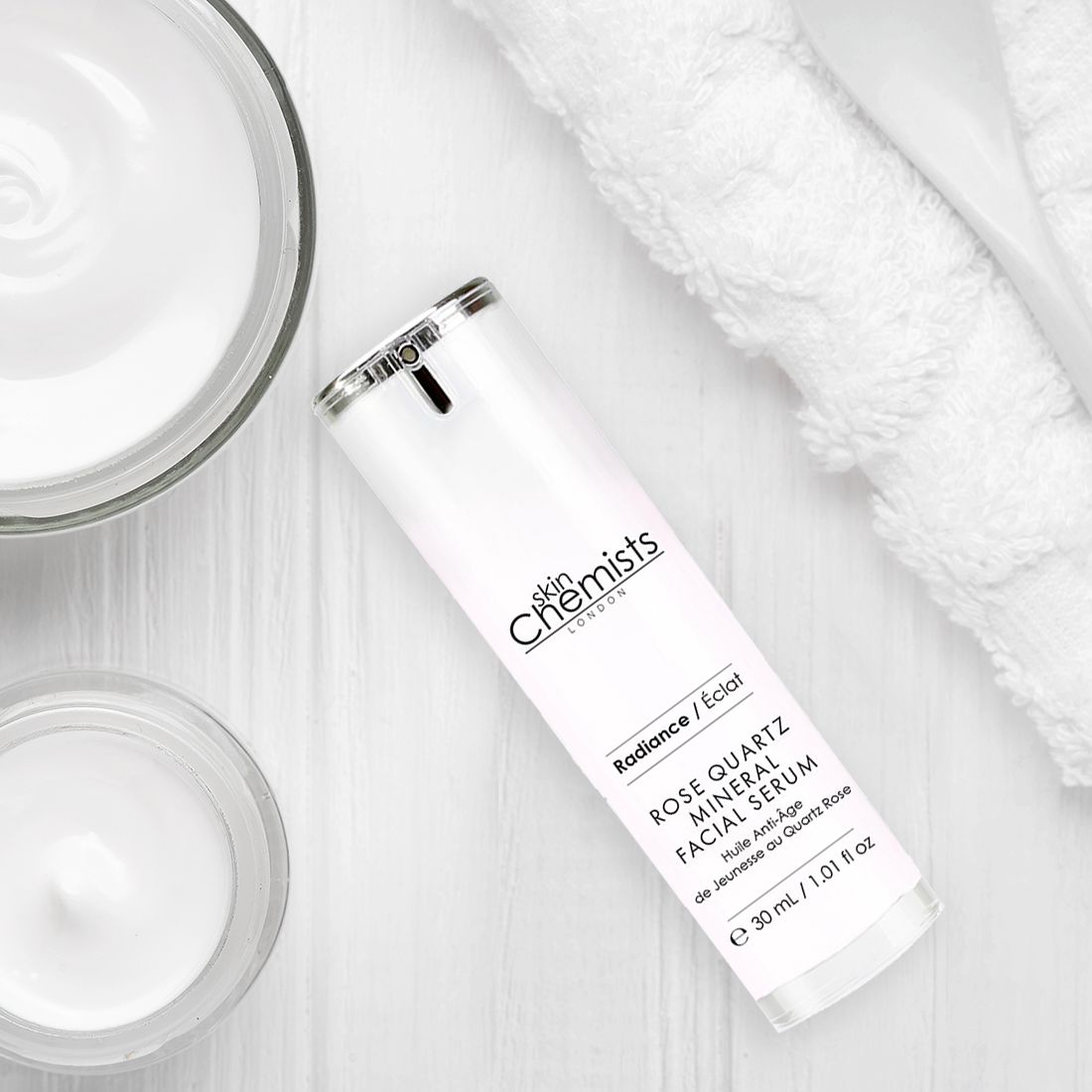 Produkt neben Cremes und Handtuch. Text: Rose Quartz Mineral Facial Serum, 30 ml. Flasche mit Pumpe.
