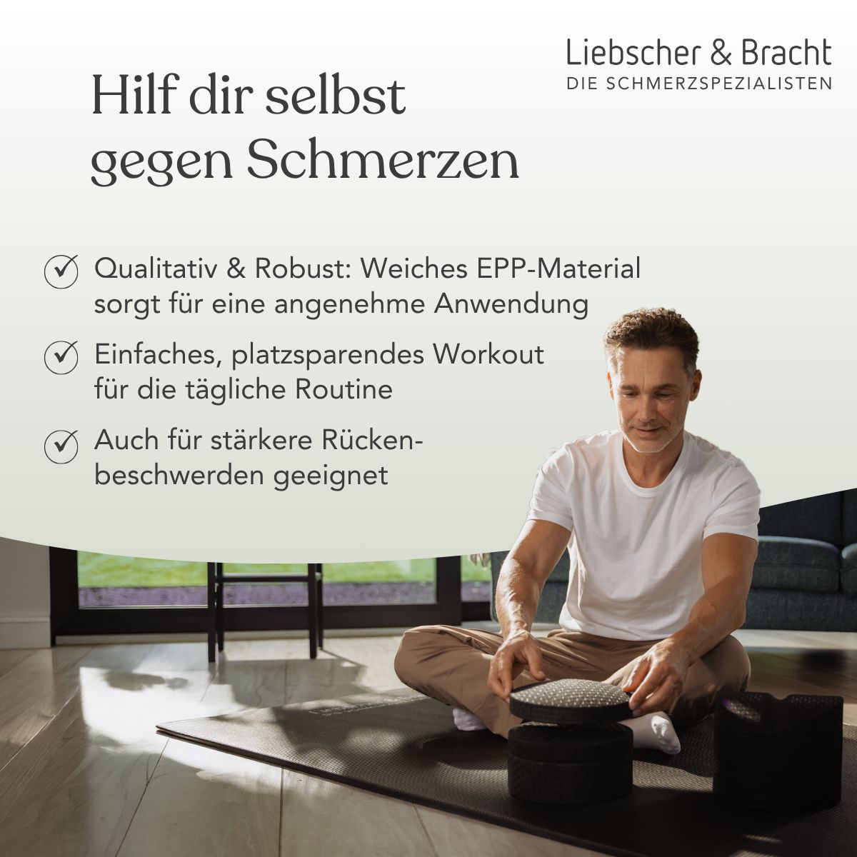 Mann sitzt auf einer Matte neben einem schwarzen Rückenretter und einem runden Element.