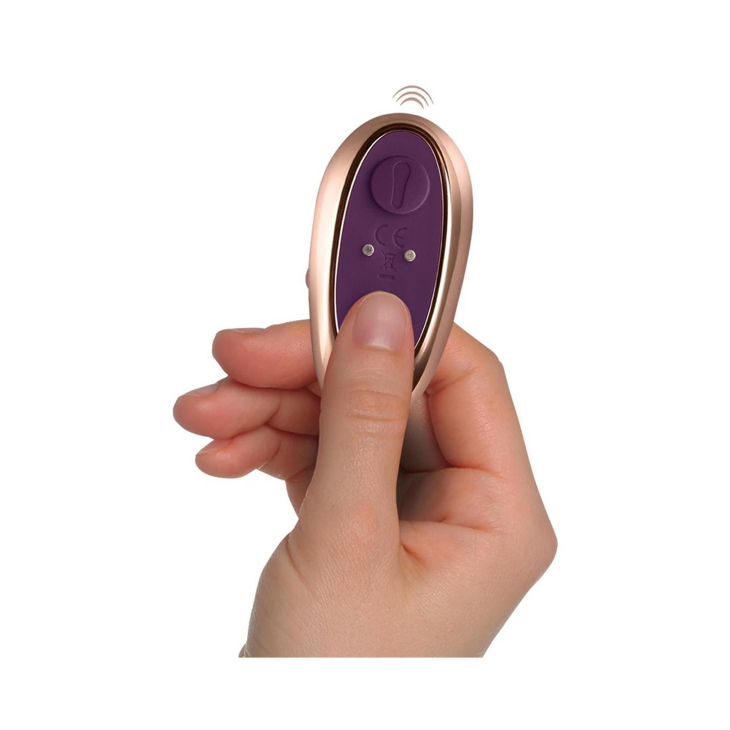 Goldfarbene Fernbedienung in Hand gehalten. Lila Knöpfe, CE-Zeichen. Drahtloses Symbol. Hand mit Hautfarbe.