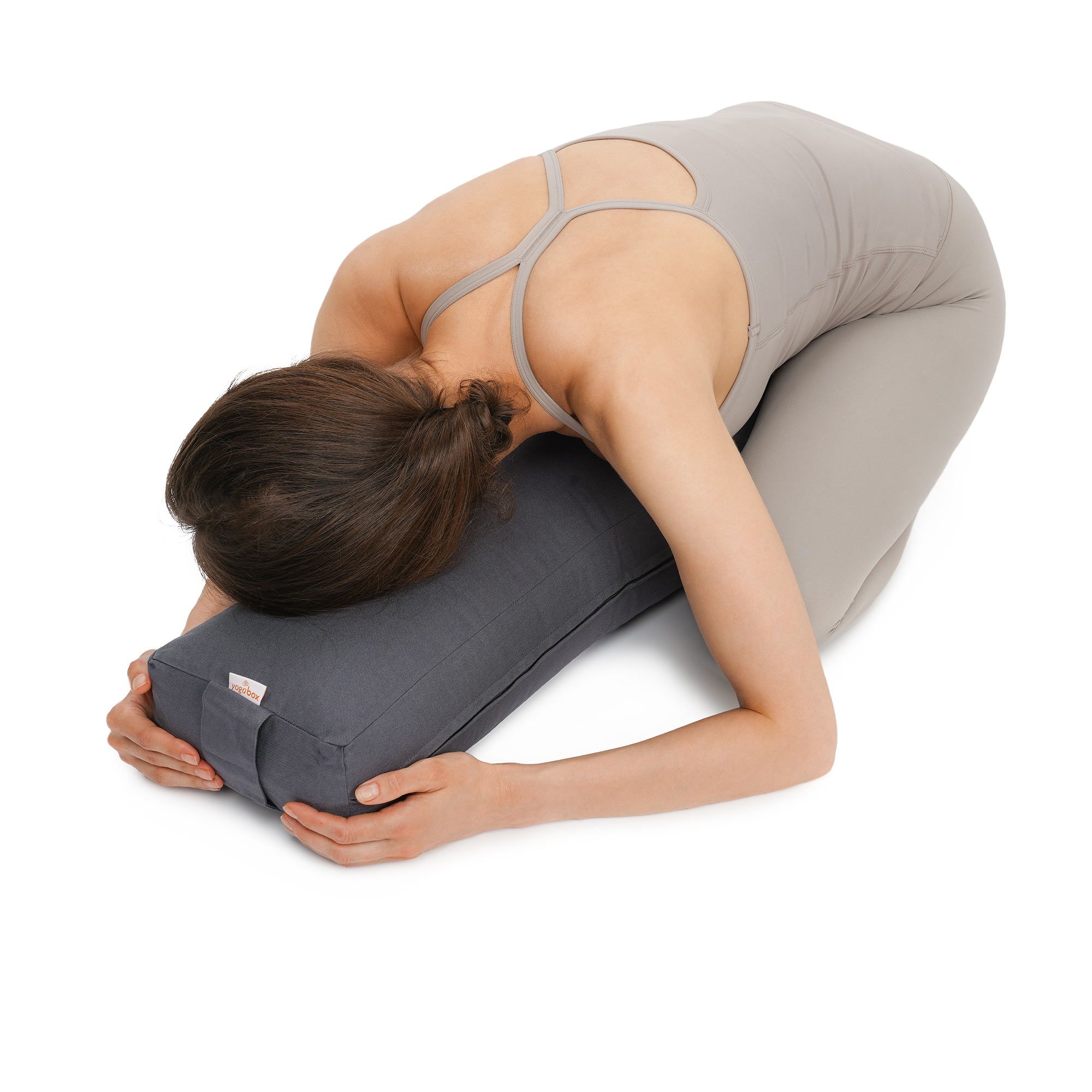 Frau in Yogapose mit Kopf auf einem grauen Yogakissen.