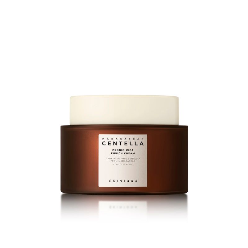 Vaso di crema marrone con coperchio bianco. Etichetta con nome del prodotto e marchio SKIN1004.