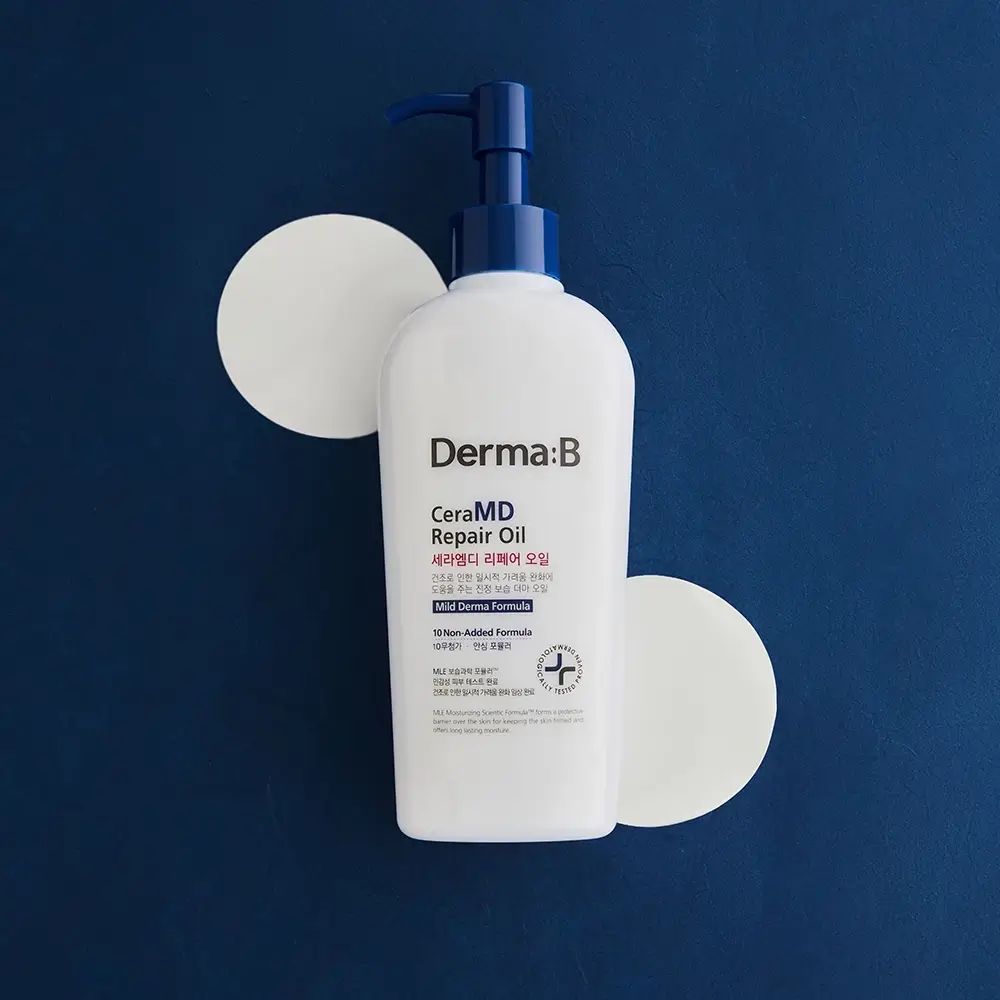 Weiße Flasche mit blauem Pumpverschluss, umgeben von zwei weißen Kreisen. Aufschrift: Derma:B CeraMD Repair Oil.