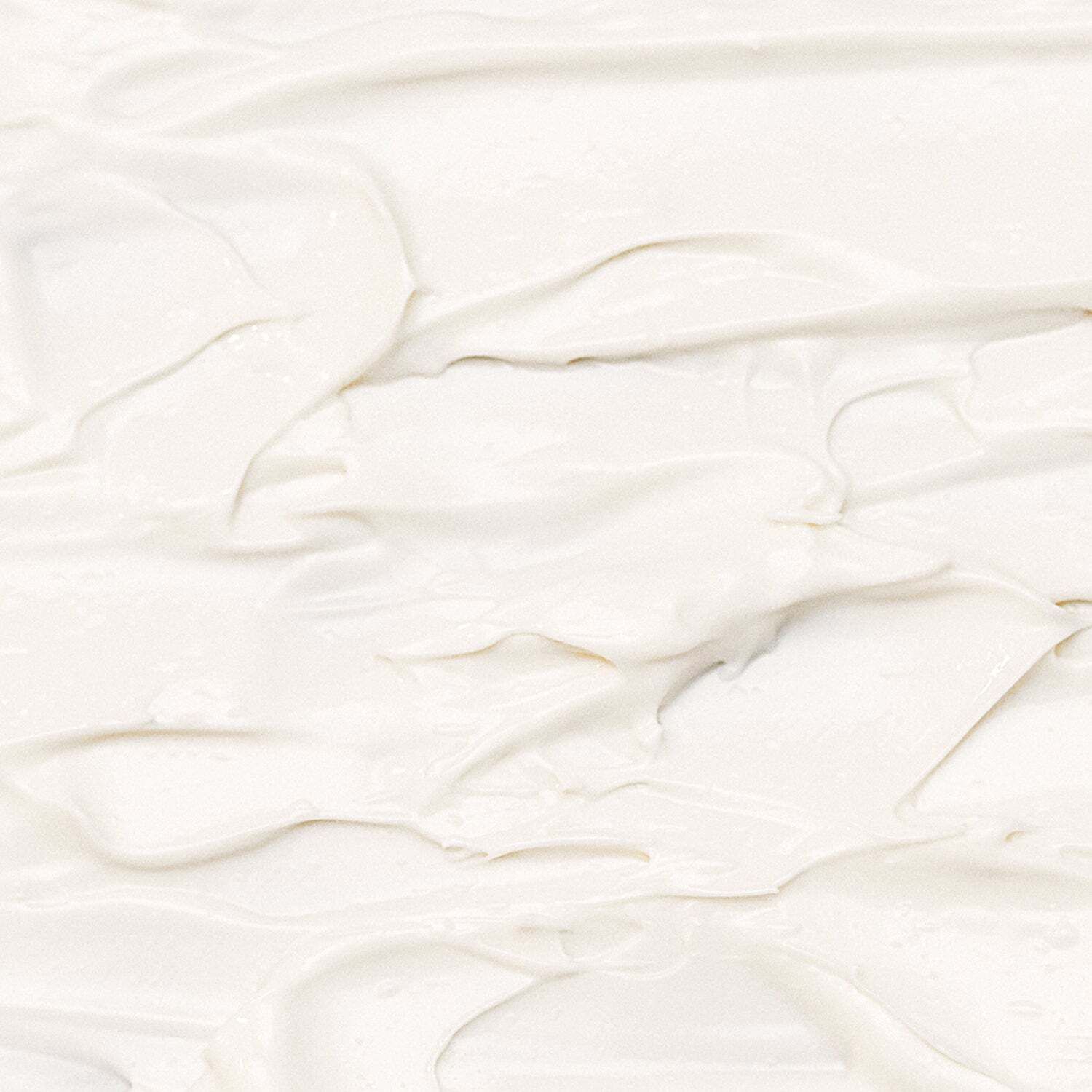 Nahaufnahme einer weißen Creme. Die Textur ist uneben und weist wellenförmige Strukturen auf.
