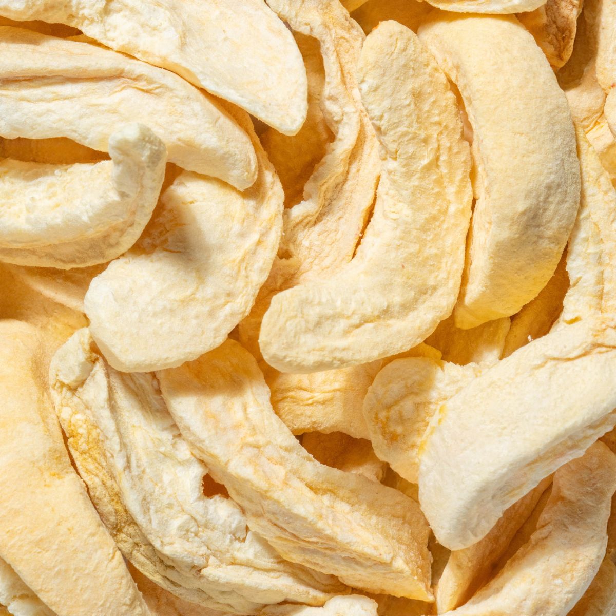 Nahaufnahme von gefriergetrockneten Pfirsich-Fruchtsnacks. Hellgelbe, getrocknete Fruchtstücke.