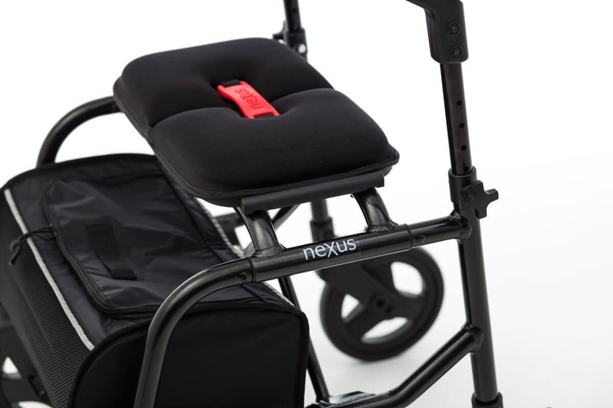 Nahaufnahme des Rollator-Sitzes mit Nexus-Logo. Schwarzes Material, roter Gurt.