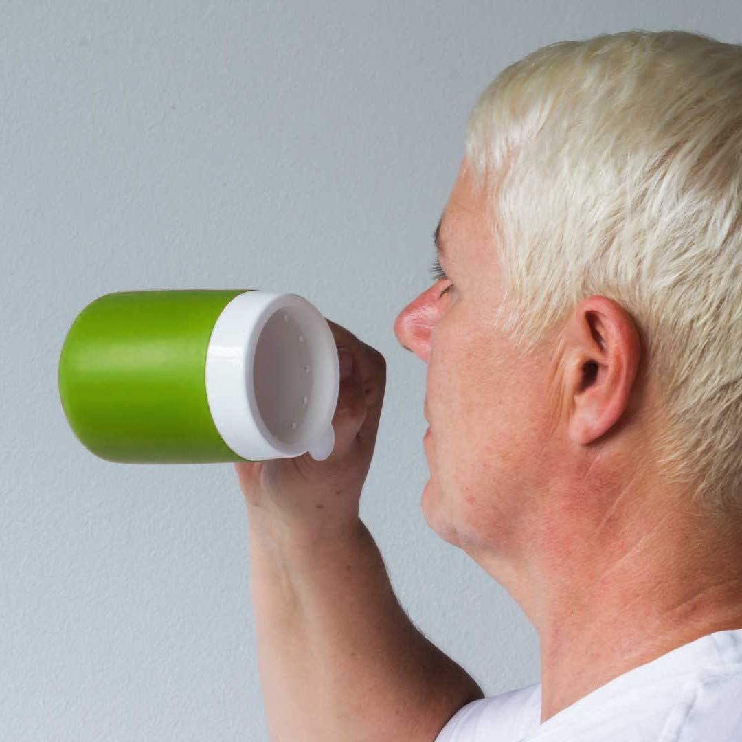 Person trinkt aus grünem Becher mit weißem Deckel. Der Becher wird gehalten.