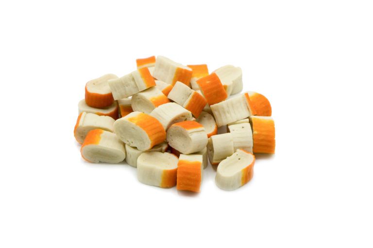 Haufen Fisch-Röllchen, weiß mit orangefarbenen Enden, auf weißem Hintergrund.