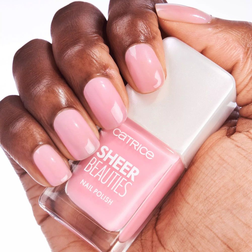 Hand mit lackierten Nägeln und Nagellackflasche. Rosa Nagellack. Marke und Produktname sind sichtbar.