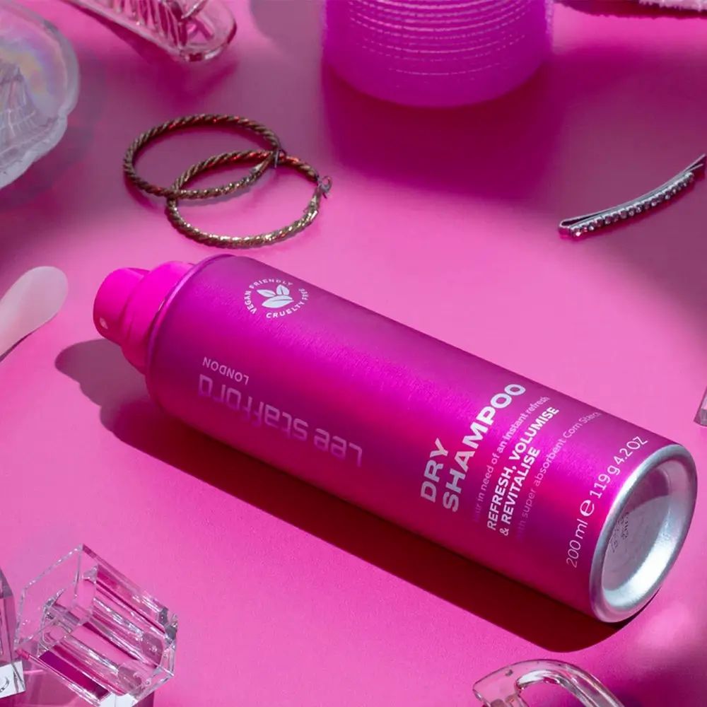Rosa Trockenshampoo-Flasche auf rosa Untergrund. Beschriftung: Lee Stafford, Dry Shampoo, Refresh, Volumise & Revitalise. Vegan und tierversuchsfrei.