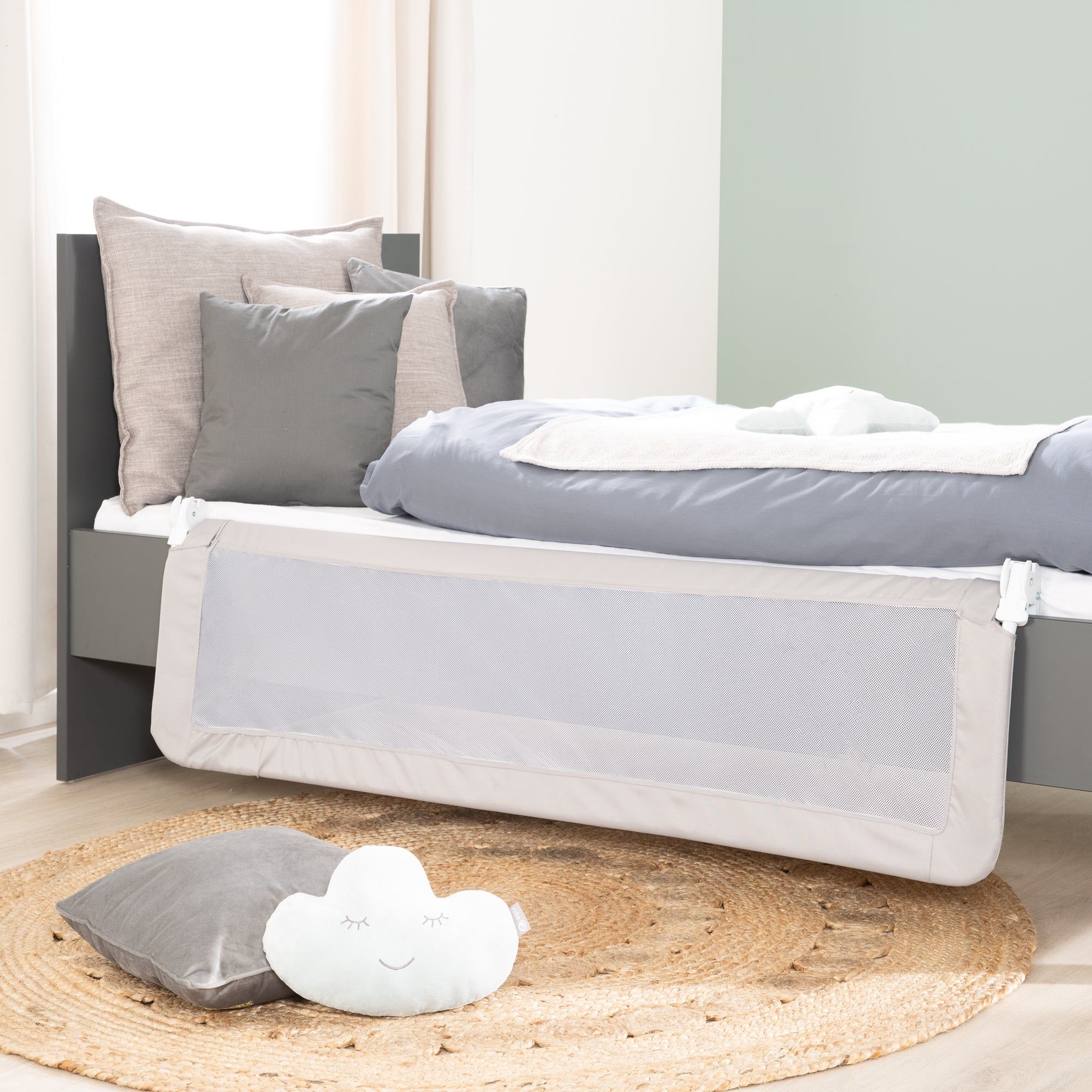 Bettgitter, weißes Netz, grauer Rahmen, an einem grauen Bett befestigt. Auf einer runden Matte.