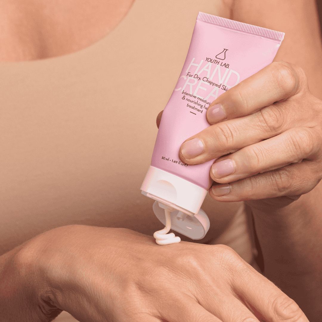 Rosa Tube mit weißem Verschluss. Creme wird auf die Hand gedrückt. Aufschrift: YOUTH LAB Hand Cream For Dry, Chapped Skin.