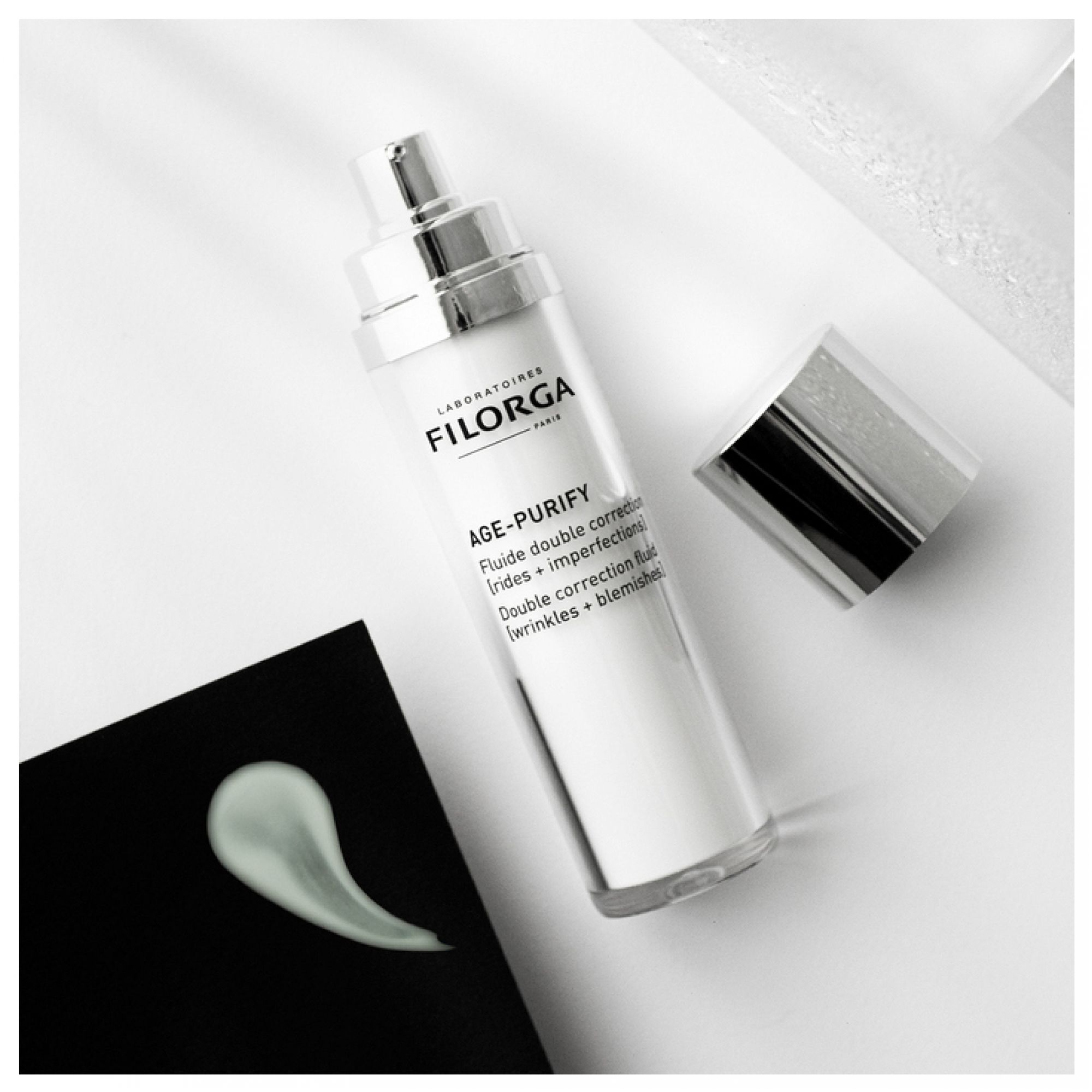 Filorga Age-Purify Fluid mit Pumpspender, abgenommenem Verschluss und Produktprobe.