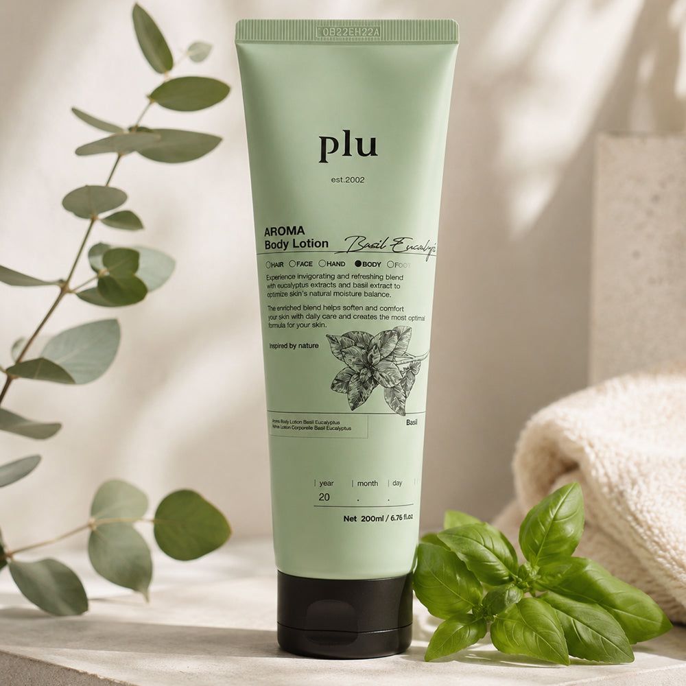 Grüne Tube 'plu AROMA Body Lotion Basil Eucalyptus' neben Basilikum und einem Handtuch.
