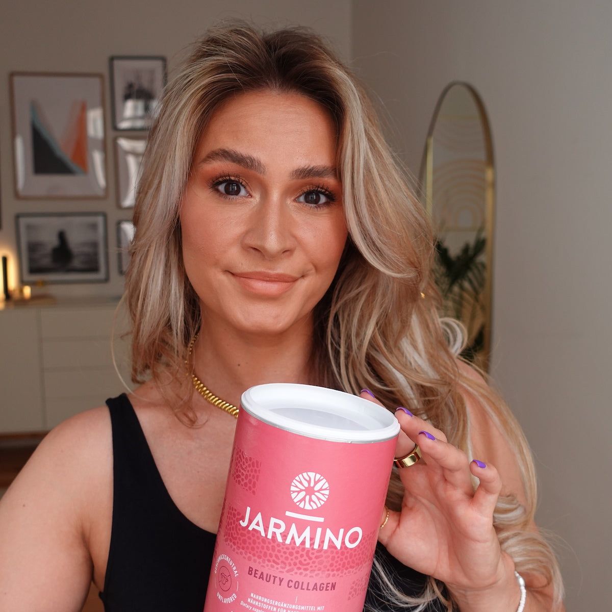 Rosa Dose mit weißem Deckel. Aufschrift: Jarmino Beauty Kollagen. Frau hält Dose.