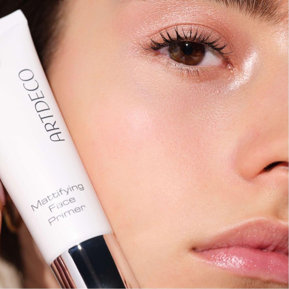 Nahaufnahme eines Gesichts. Weiße Tube mit Artdeco und Mattifying Face Primer. Haut mit Primer.