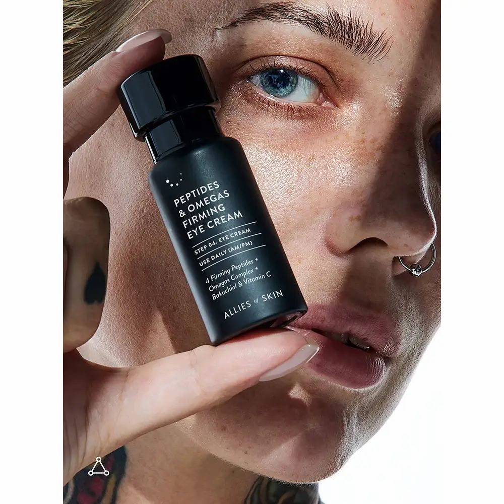 Person hält Flasche 'Peptides & Omegas Firming Eye Cream'. Text: 'ALLIES OF SKIN'.