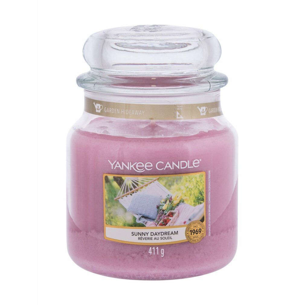 Yankee Candle Duftkerze Sunny Daydream. Rosa Kerze im Glasbehälter mit Deckel. Etikett mit Bild einer Hängematte. Gewicht: 411 g.