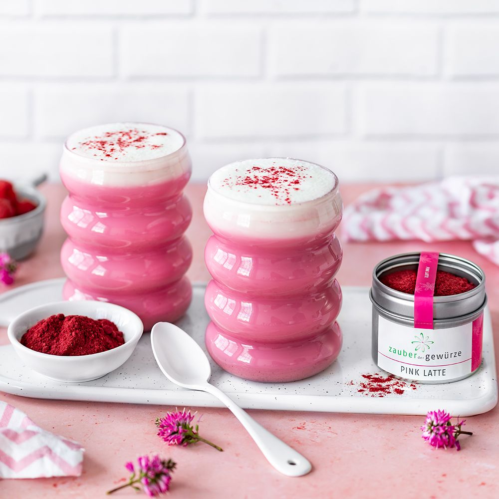 Zwei Gläser Pink Latte mit Schaum. Dose "Zauber der Gewürze Pink Latte". Schale mit Pulver, Löffel. Tablett.