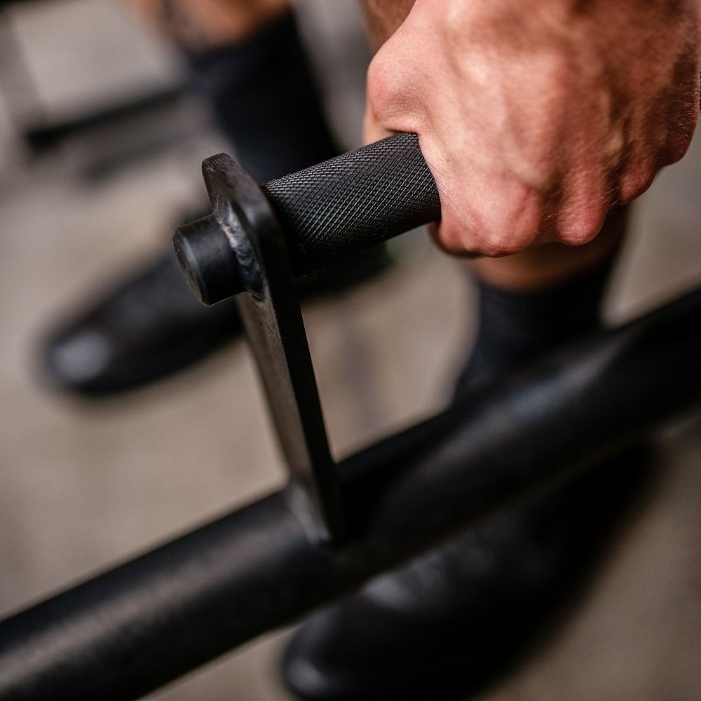 Nahaufnahme der Hand, die einen Griff einer Farmers Walk Bar hält. Schwarzer Griff mit Textur.